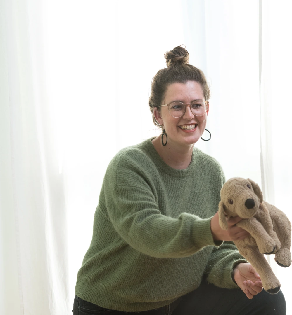 Dorothea Singer hält einen Hund-Kuscheltier in ihrer Praxis Soma & Raum Stuttgart